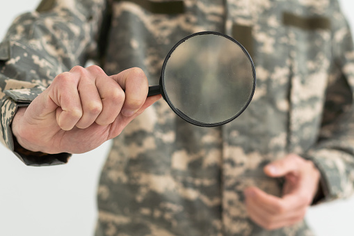 military man holding a magnifying glass.