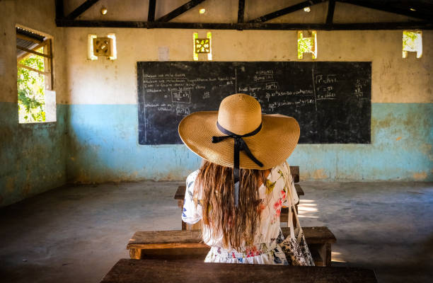 A cute preschooler asian girl makes a thumbs up sign while walking outside her classroom. At a provincial primary school in Bohol.