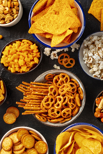Salty snacks, party mix, top shot. A variety of appetizers in bowls. Potato and tortilla chips, crackers, popcorn etc
