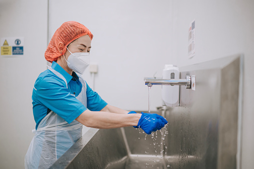 Asian Chinese factory female worker washing hands cleaning herself before entering clean room