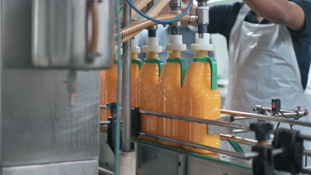 Orange Juice factory automation operating filling up bottle with juice