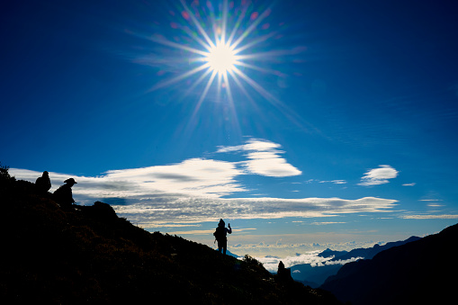 Woman hiker walking alone on top of a mountain in silhouette.