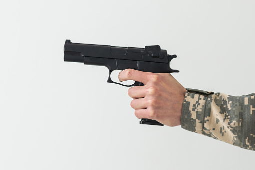 Military man holding a gun in hand.