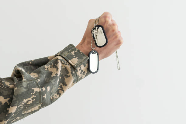 istock Man in camouflage uniform holding military ID tags over wooden background. 1490318079