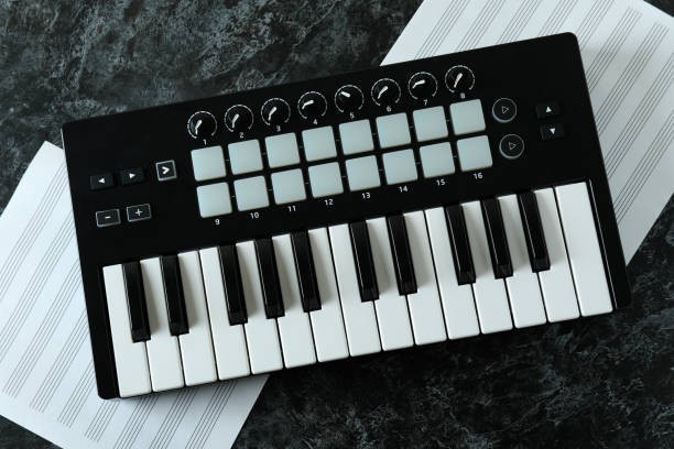 istock Midi keyboard and music sheets on black smokey table 1490319813