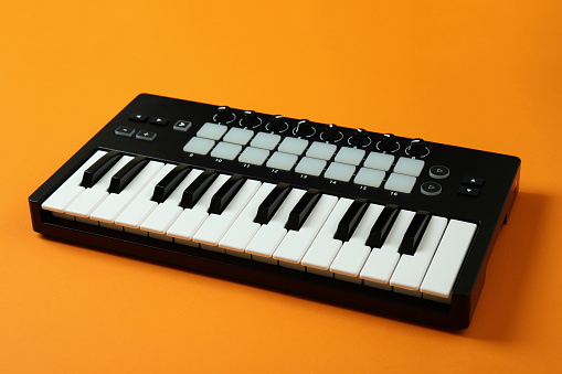 Midi keyboard on orange background, digital musical instrument