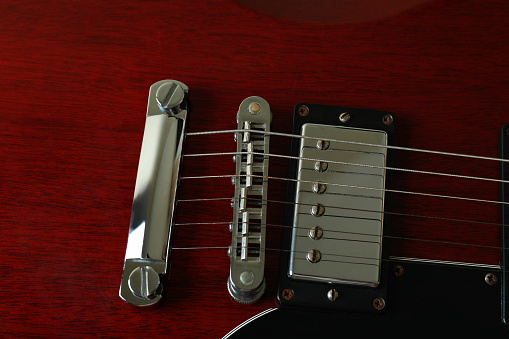 Close-up showing the pickup selector switch and volume control on a vintage style electric guitar, with the guitar's strings, pickguard, bridge and pickups visible in the background.