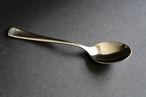 Close-up of metal stainless steel tea soon with black background and metal spoon. Photo taken May 15th, 2023, Zurich, Switzerland.