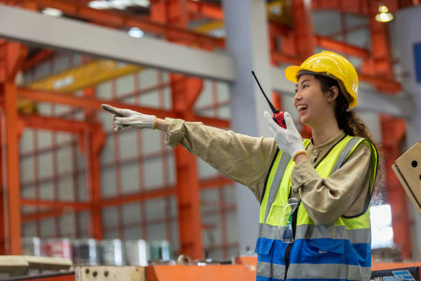istock happy smile women engineer holding walkie talkie point your finger forward quality control standing at machine of factory warehouse. professional engineering machinery workshop. 1490325809