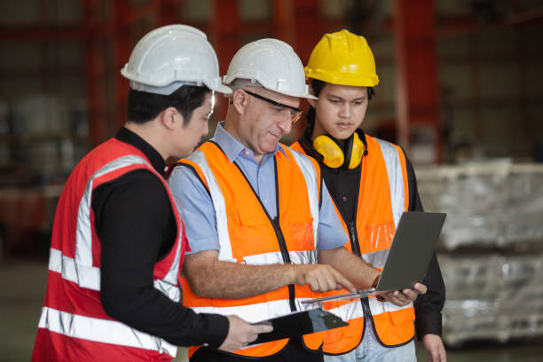 istock Three man industrial engineers wear hard hats and uniform using laptop talking project of factory inside heavy industry manufacturing. Supervisor teaching work to employee. 1490326218