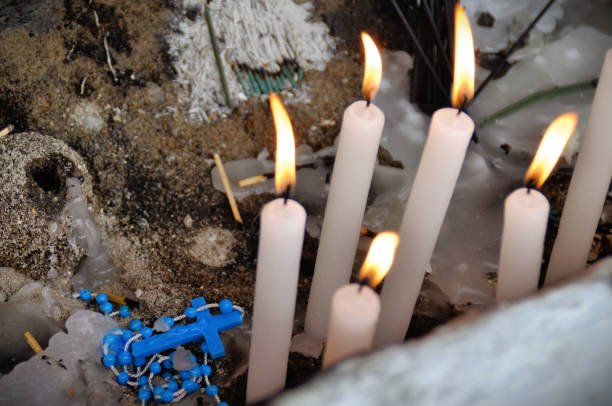 Blue crucifix among lit candles in the cemetery wake