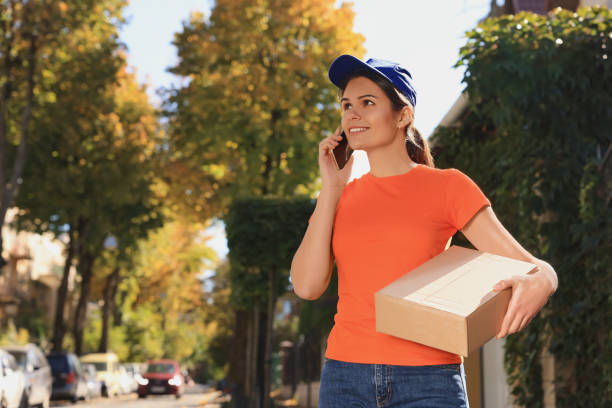 istock Courier with parcel talking by smartphone on city street 1490329519
