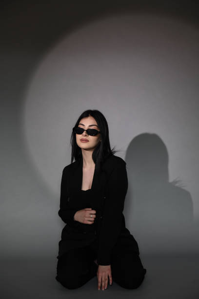 istock Confident Female With Sunglasses And Suit Kneeling Down On Background 1490332781