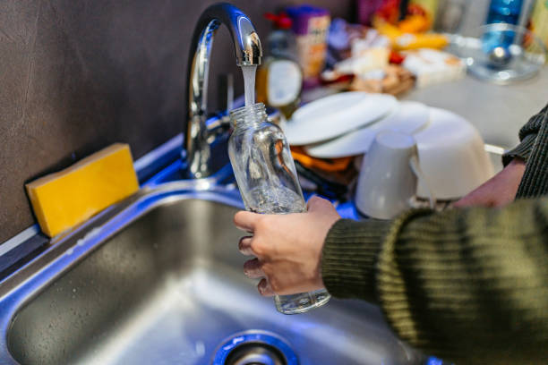 istock Young Woman Refiling Her Glass Water Bottle With Water 1490337911