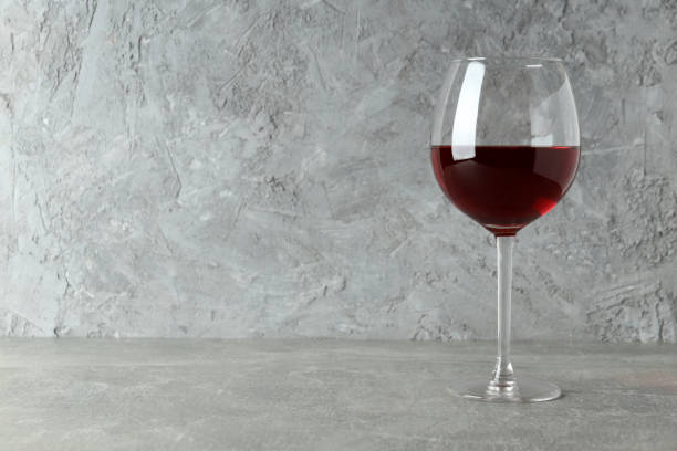 istock Glass of red wine on gray textured table 1490338063