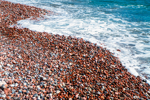 Ripples of light reflected over submerged rounded pebbles at the shoreline.  Quintin Bay, County Down, Northern Ireland.