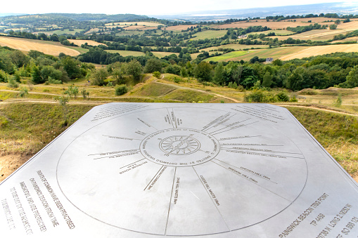 Painswich, UK-August 2022; Close up view of the topographic steel plate on top of Painswick Beacon along the Cotswolds Way with panoramic view over the hilly landscape