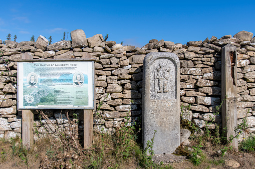 Lansdowne Hill, Cotswolds, UK-August 2022: Close up of information sign and battlefield marker against stone wall, where The First English Civil War battle of Lansdown was fought on 5 July 1643