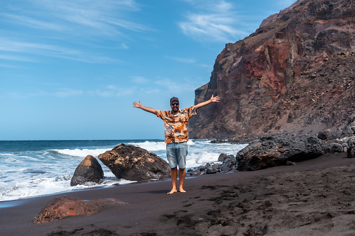 Tourist enjoying vacation on the black volcanic sand beach of Ingles in Valle Gran Rey on La Gomera, Canary Islands