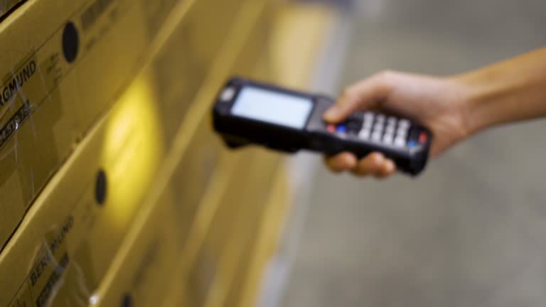 Close up hand scanning products with barcode scanner in warehouse.