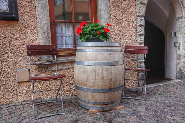 A rustic, wooden barrel-shaped table stands atop a brick patio in a sunny outdoor setting