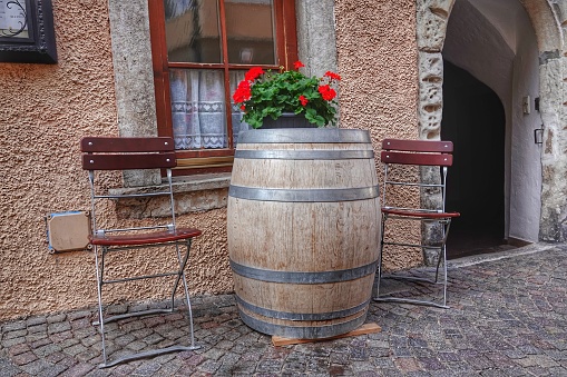 A grouping of old antique oak barrels as pots with a variety of flowers and plants  in the background outdoors on a patio