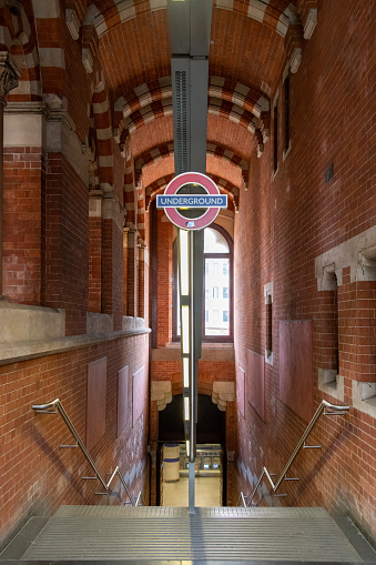London, England-August 2022; Vertical view of stairs in St Pancras station in Gothic Revival architecture leading to the underground platform with sign above stairs
