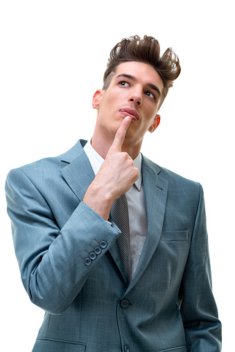 Portrait of mature man wearing navy blue jacket and white shirt, looking away. Studio shot of male entrepreneur against grey background.