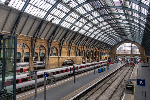 London, England-August 2022; View over the platforms with waiting trains and passengers in Kings Cross station in Gothic Revival architecture with arched roof of steel and glass