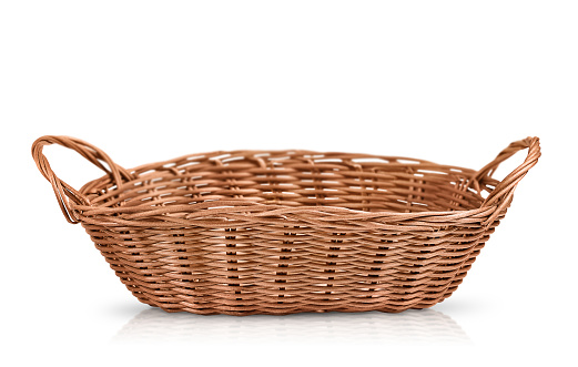 an oval brown wicker basket is highlighted on a white background by shadow and reflection