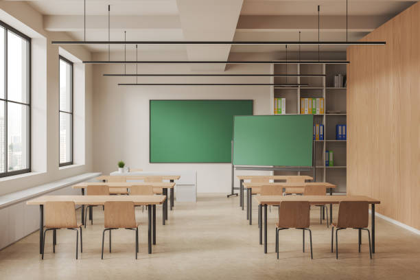 istock Stylish beige classroom interior with desk in row and chalkboard mockup 1490349154