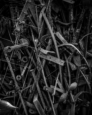 A pile of old, rusty tools including in grayscale