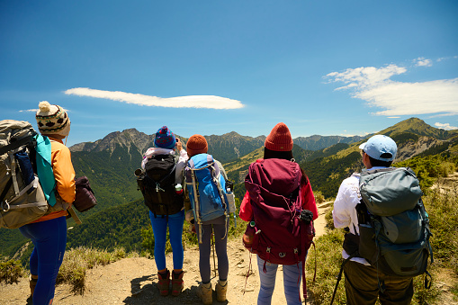 Hikers stand on top of a mountain looking at view.