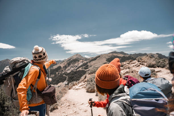 Hikers stand on top of a mountain looking at view.