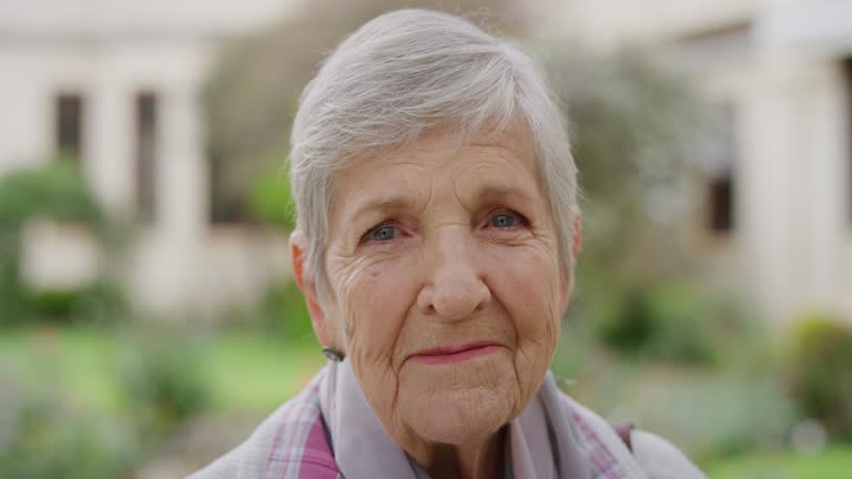 close up portrait of senior caucasian woman smiling happy looking at camera enjoying sunny day in park