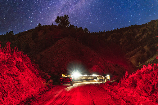 Parking and Exploring at Night - Person wearing headlamp walking around exploring area near parked vehicle during dark skies along dirt road in backcountry setting.