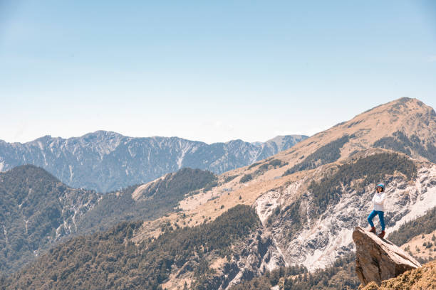 A peaceful mountain range adorned with dense green forests cascading down the slopes, illuminated by the gentle light of a clear day. The sharp ridges and natural contours create a mesmerizing view, ideal for nature photography and outdoor adventures.