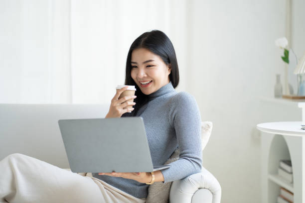 istock Pretty Asian woman having a relax time drinking a coffee and using laptop. 1490359487