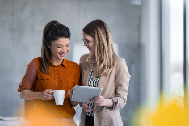 istock Two cheerful businesswomen using digital tablet in the office. 1490362254