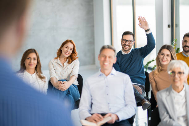 istock Young man raising a hand to ask a question on an engaging seminar. 1490363404