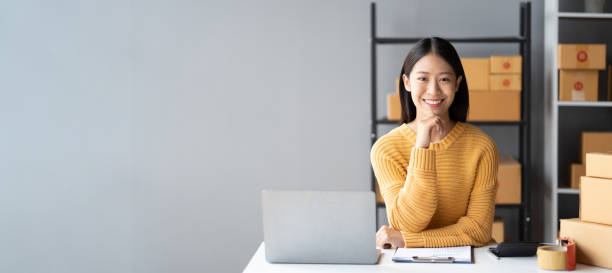 Portrait of young Asian small business owner working in her room while using laptop computer. Sme business concept.