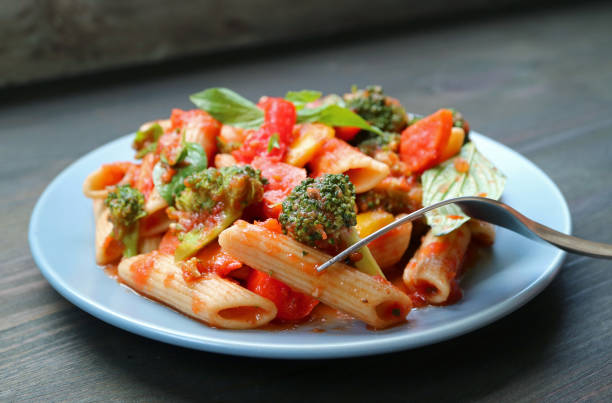 Fork Picking Flavorful Penne with Roasted Vegetables in Tomato Basil Sauce