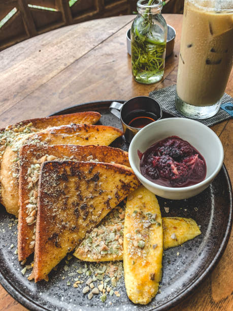 istock toast sprinkled with peanuts, drizzled with maple sauce and garnished with sliced ​​bananas, then added strawberry jam for breakfast accompanied by a glass of iced coffee milk 1490373773