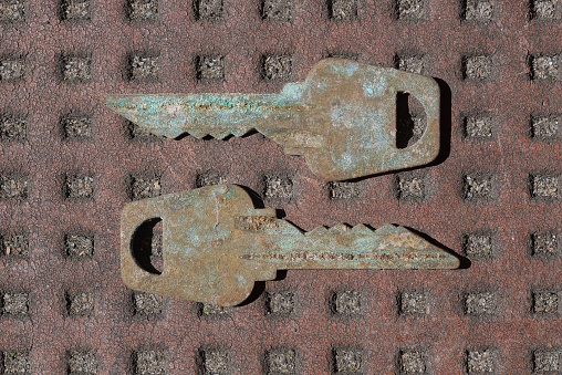 two old gray metal keys in rust lie on a brown table