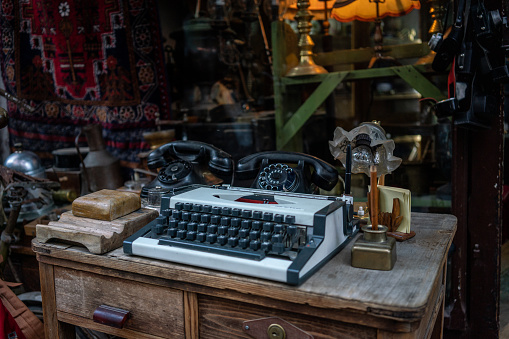 old type writer and old telephone are on the old wooden table focus on foreground horizontal travel still