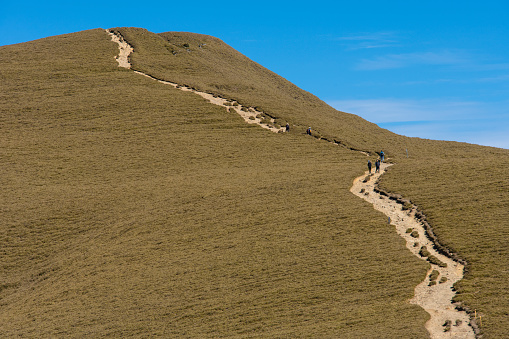 Hikers walking alone on top of a mountain.