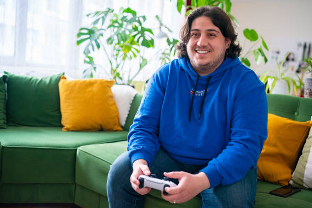 istock Full Figured Young Man playing video game at home 1490380838