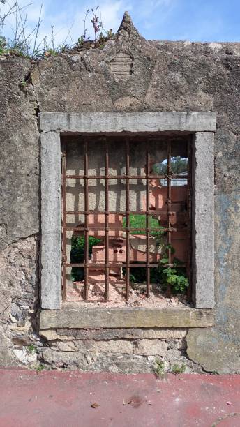 istock High fence with window and grille. Antique window covered with red brick 1490380930