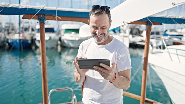 Middle age man smiling confident using touchpad at boat