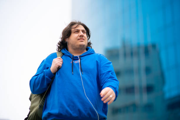 istock Full figured young man walking in the city with backpack 1490383392